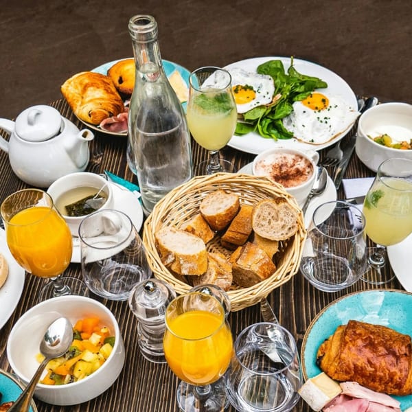 A Harry's Hilltop deli breakfast spread with pastries, eggs, fruit, and drinks on a wooden table.