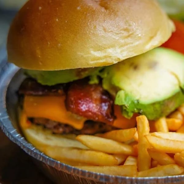 Harry's Hilltop burger with avocado, bacon, cheese, and fries in a foil container.